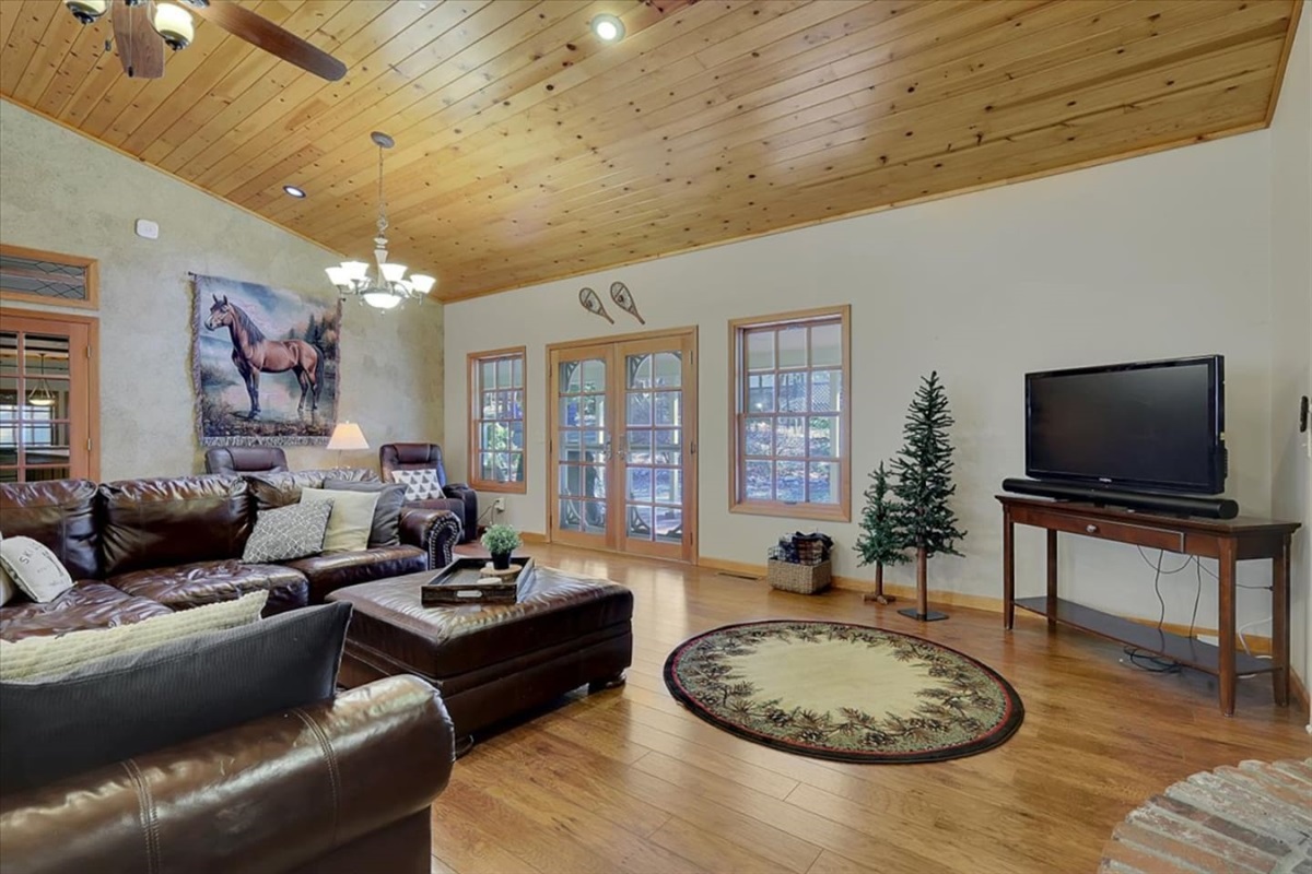 Living room with leather seating, wood ceilings, TV, and a relaxed cozy feel.
