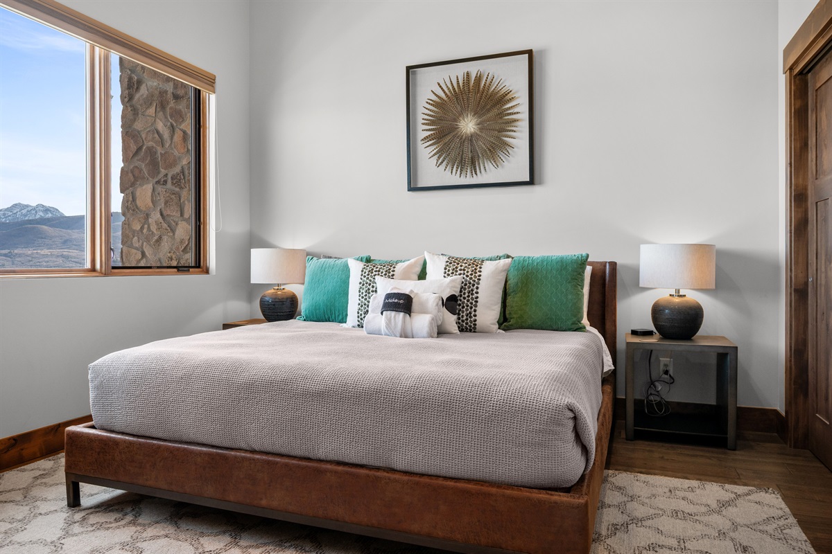 Spacious primary king bedroom with modern furnishings and mountain views