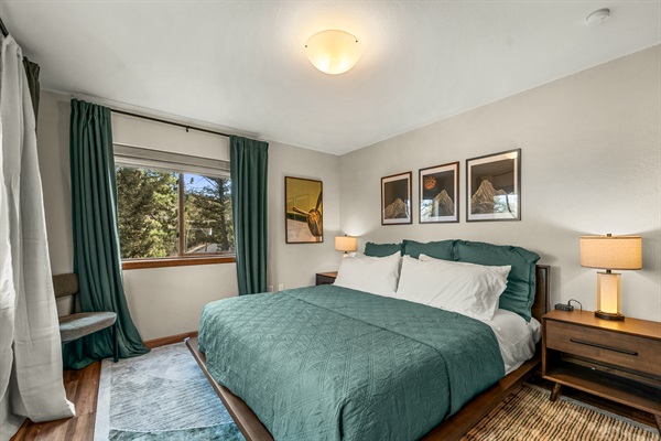 🛌✨ Cozy, stylish main-level bedroom with a king bed, warm bedside lighting, and peaceful pine views 🌲—a perfect spot to recharge after a day outdoors.