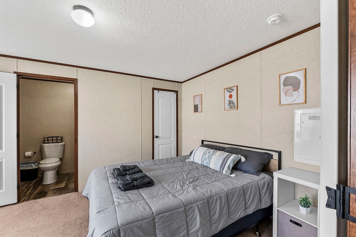 Relaxing sleeping space with neutral tones, comfortable bedding, and an en-suite bathroom just steps away.