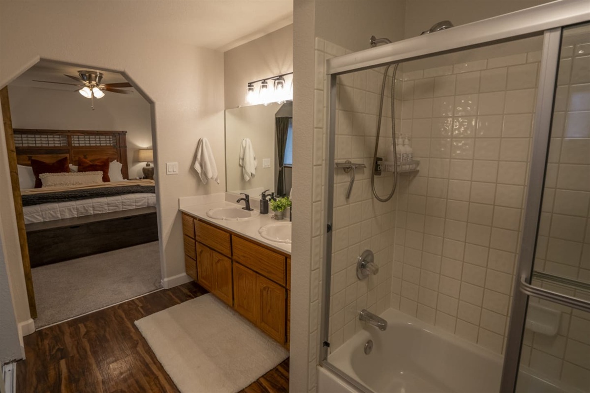 Ensuite-style bathroom with double sinks, tub/shower combo, and easy access from the bedroom.