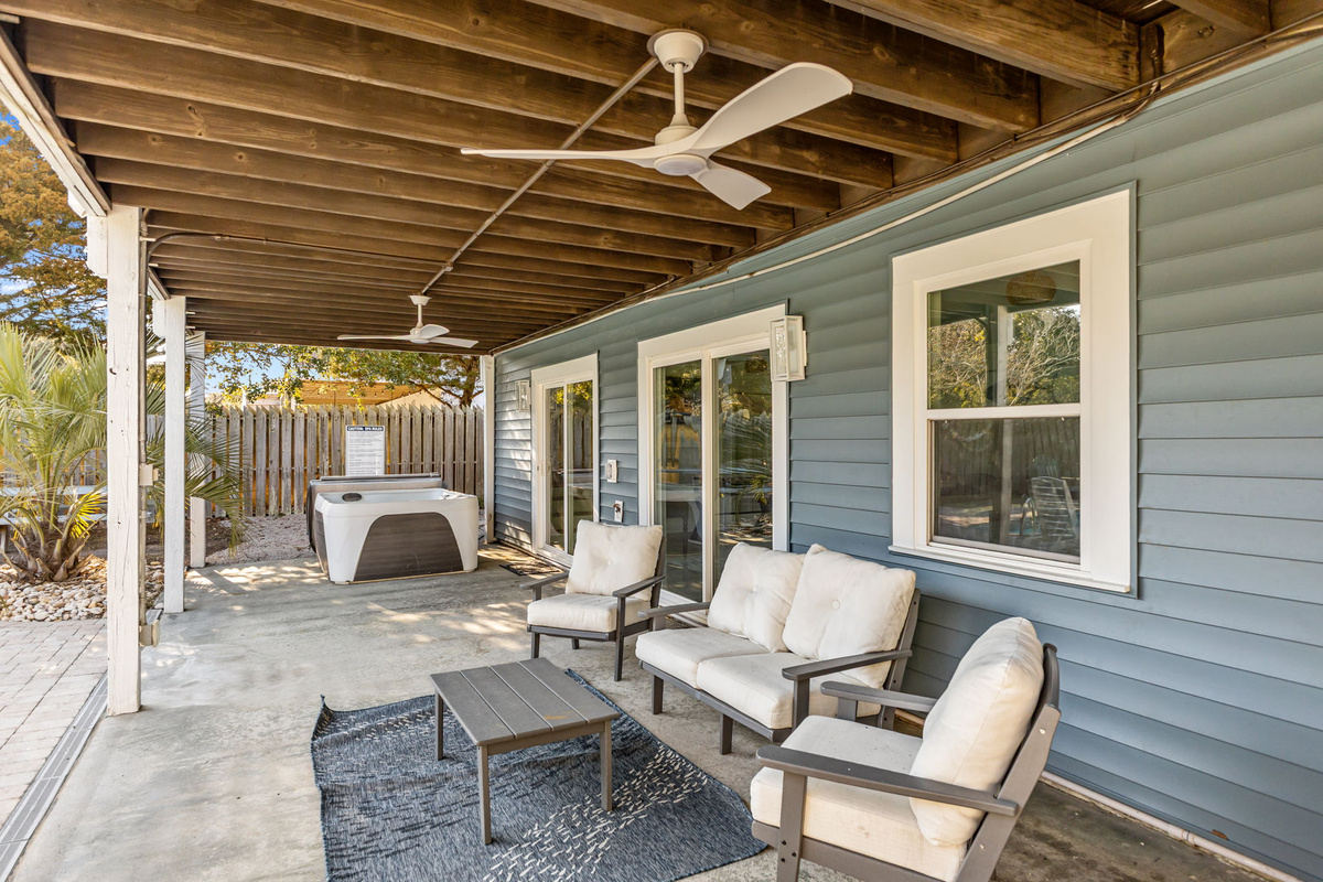 Relax beneath the covered patio with comfortable outdoor seating, ceiling fans, and easy access to the private hot tub