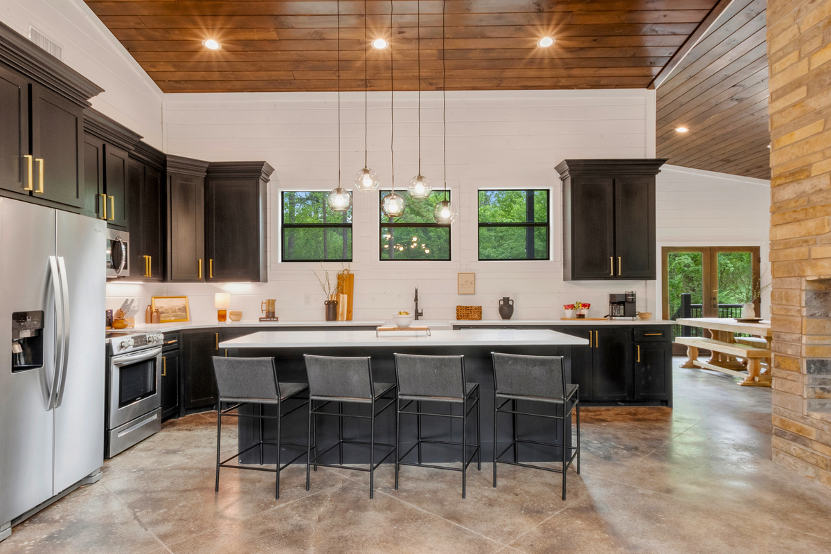 Cook in style in this sleek, modern kitchen featuring dark cabinetry and gold accents, all while being part of the conversation at the spacious island.