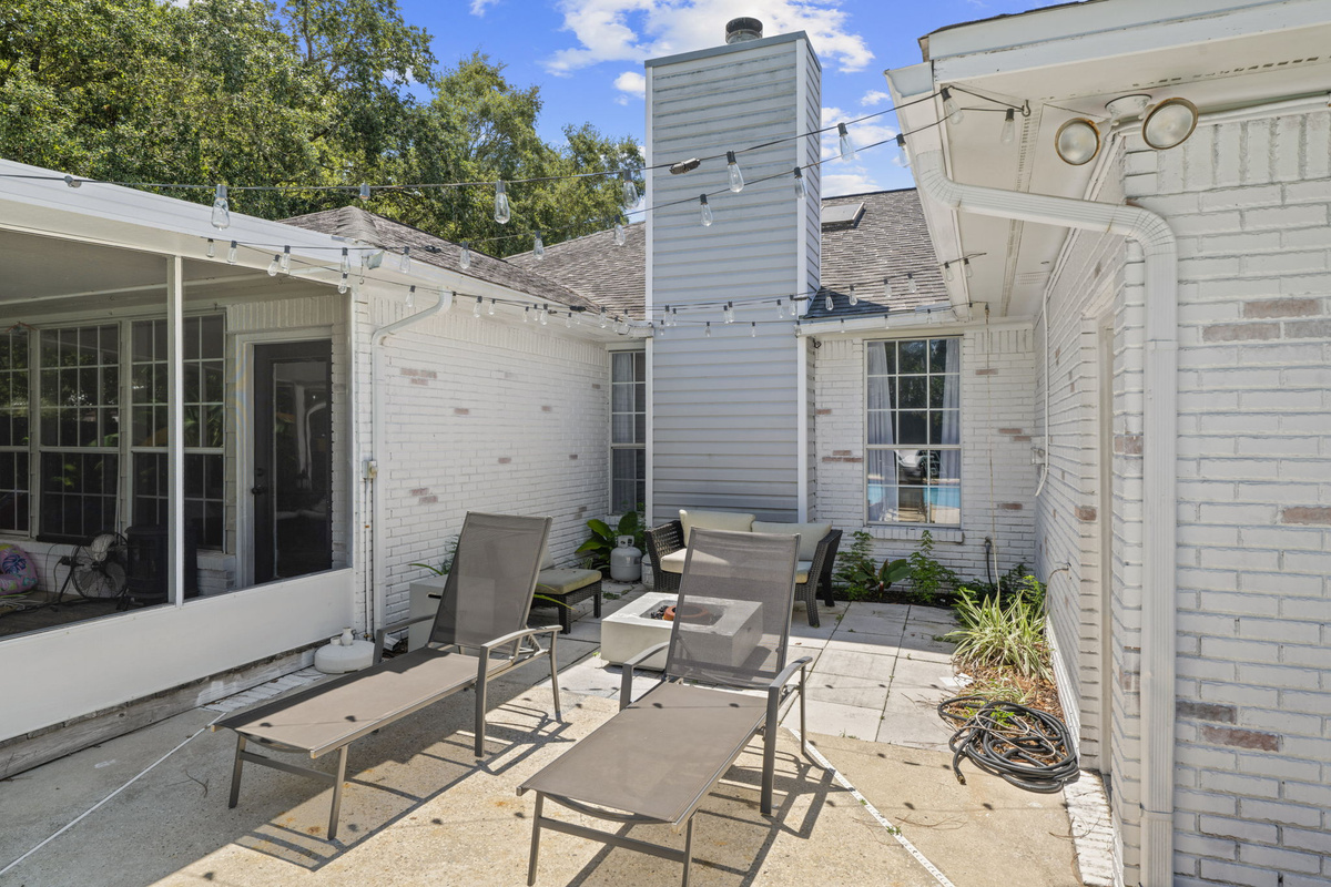 Unwind by the fire table under string lights in this cozy courtyard patio, perfect for evening gatherings.