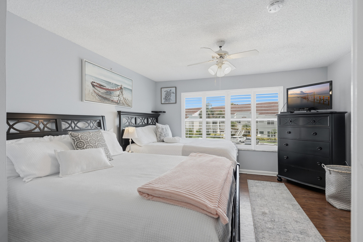 The spacious guest bedroom features two queen-size beds, making it a comfortable retreat for family or friends. With plenty of room to relax, it's an ideal space for guests traveling together.