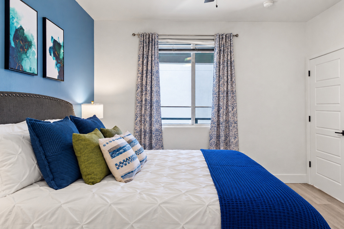 - Cozy bedroom featuring soft blue accents and a private ensuite bathroom view   - Elegant bedding and warm lighting create the perfect relaxing retreat space   - A bright peaceful setting designed for restful nights and comfortable mornings