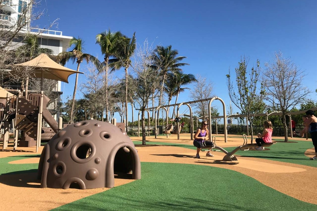 Beach playground at Allison Park with sun shades and a zipline, kids run safely while parents take a breather