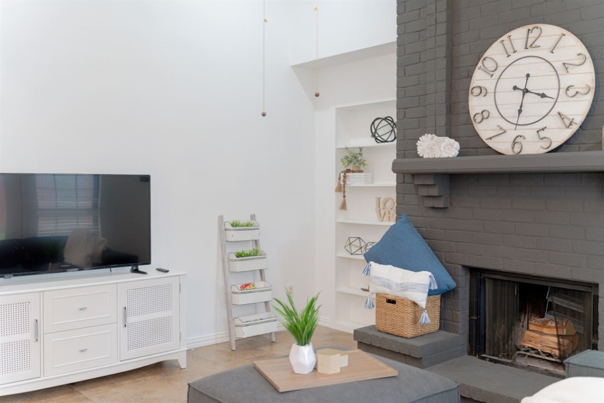 Spacious living area with fireplace, TV, and stylish shelving.
