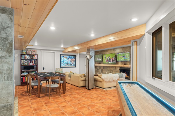 Downstairs rec room with multiple TVs, kitchenette, shuffeboard, and arcades