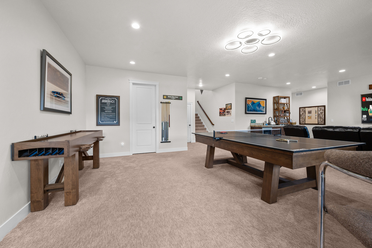 Bright and inviting recreation room featuring ping pong, shuffleboard, and easy access to the fitness area.