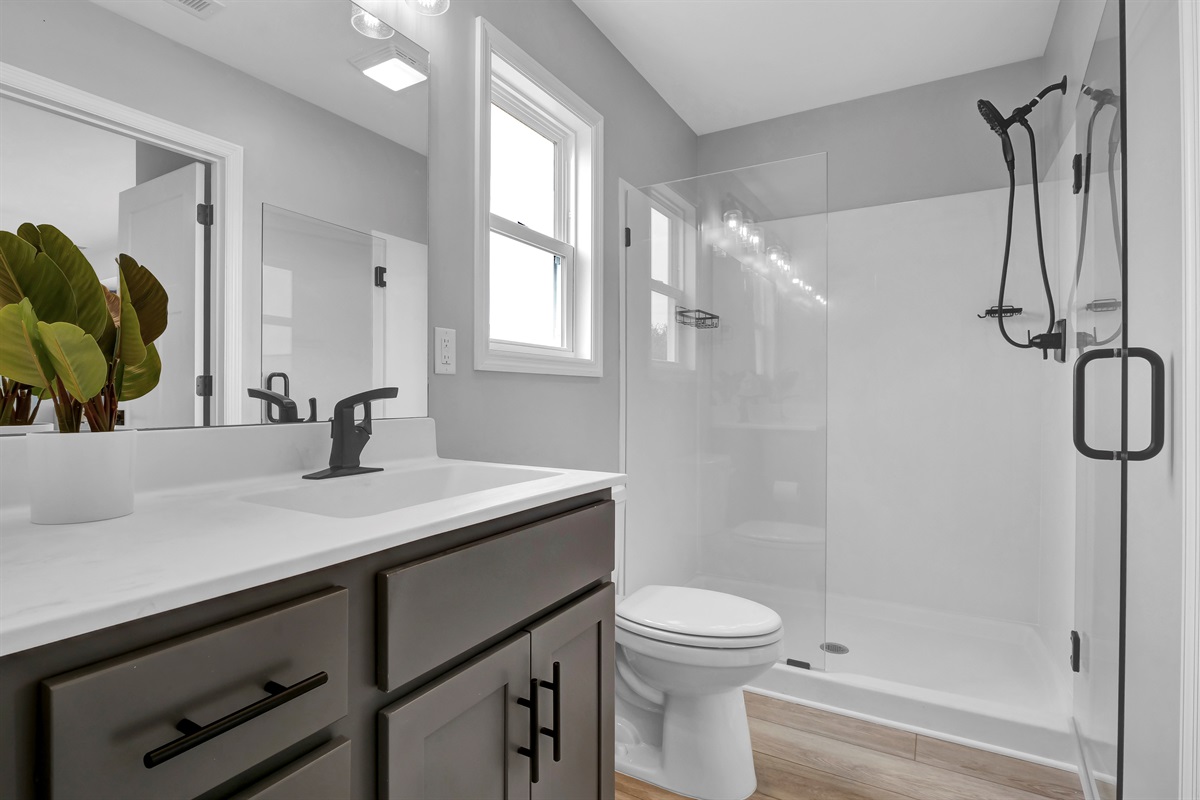 Step into your private bathroom featuring sleek glass shower doors and updated finishes
