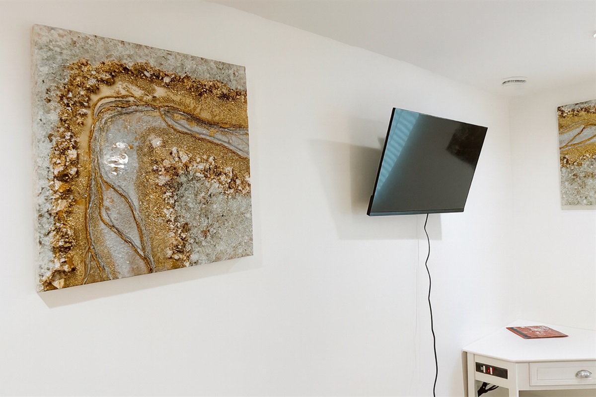 Wall-mounted Smart TV and corner desk area in The Gold Room, perfect for streaming, reading, or catching up on work during your stay.