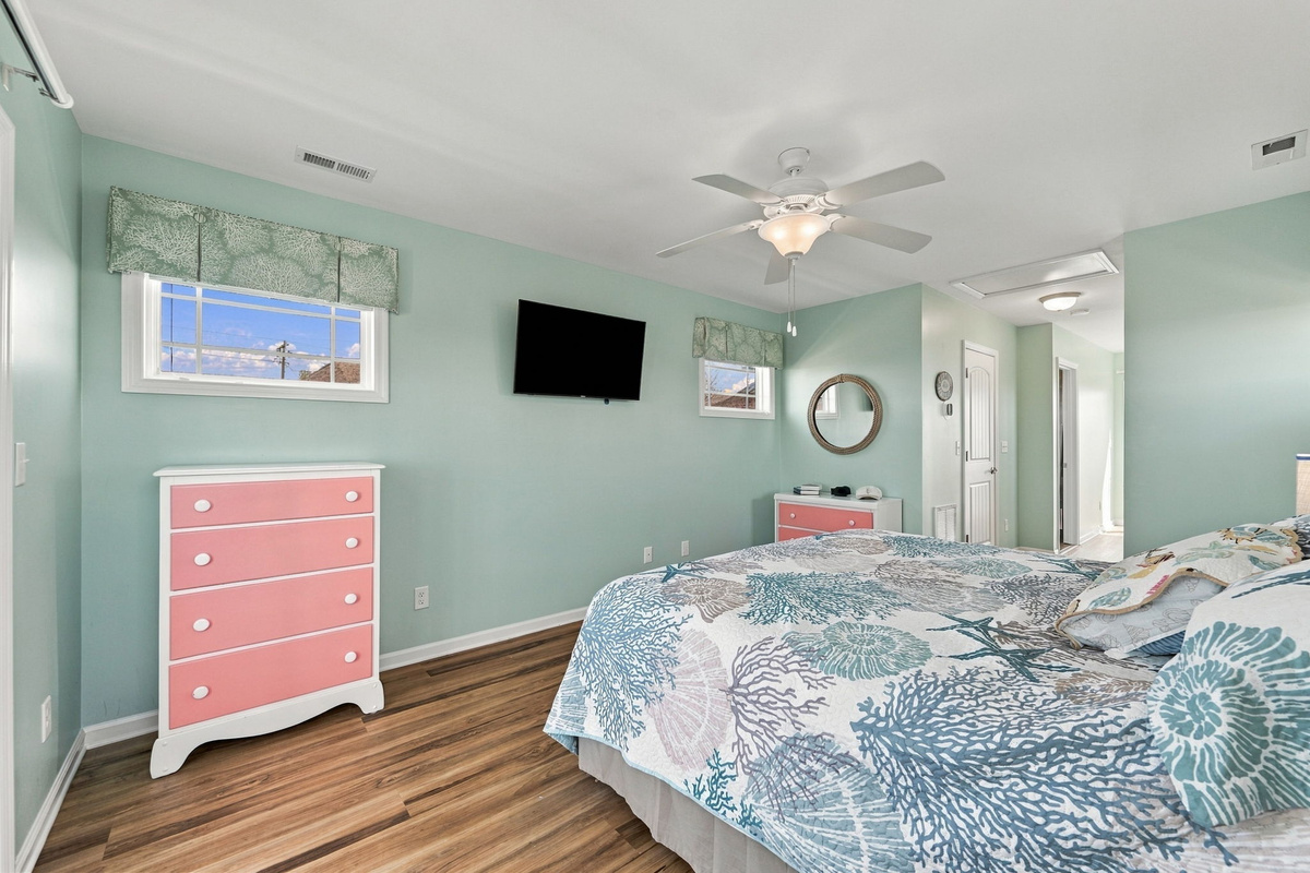 Bright and airy bedroom featuring coastal décor, a wall-mounted television, and comfortable furnishings