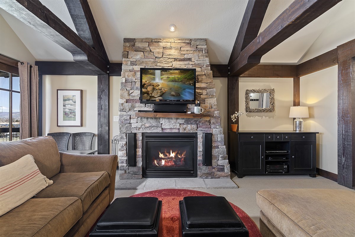 An open-concept living space seamlessly blends comfort and design, with a stunning stone fireplace serving as the focal point for relaxed luxury.