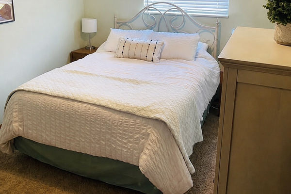 Bedroom with white linens and wooden wardrobe