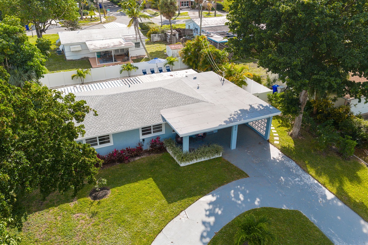 Soaring aerial perspectives highlight the home’s tranquil Pompano Beach neighborhood, private backyard oasis, covered carport, and extended driveway with space for 3 cars.
