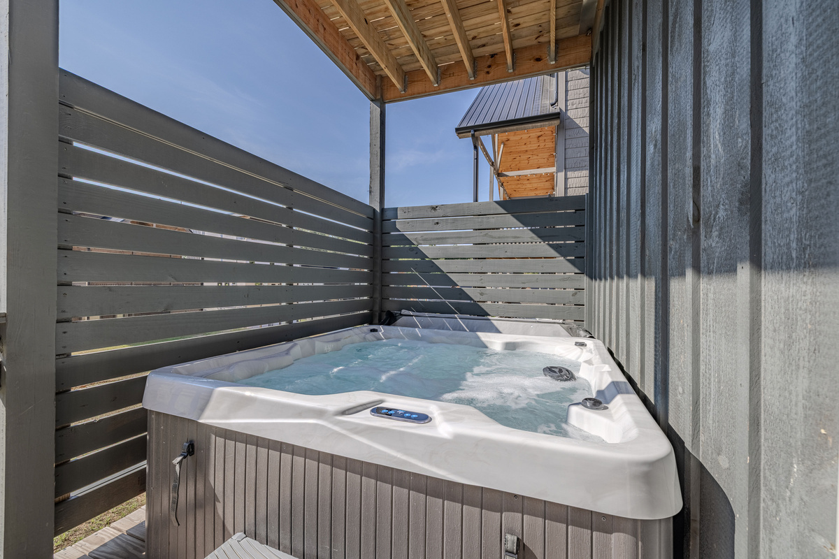 The hot tub is tucked into a deck area with privacy screening.