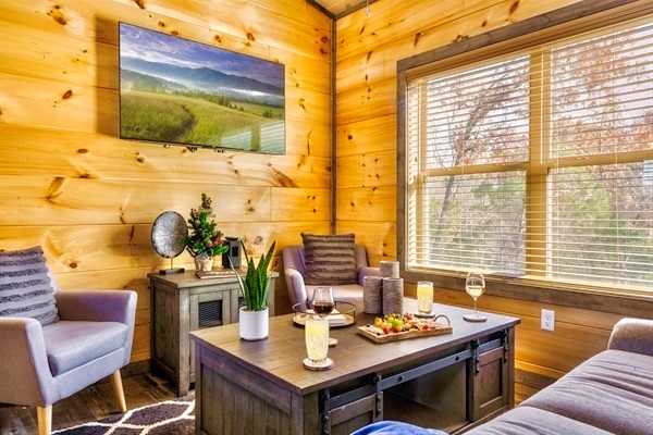 Snuggle up in the inviting living room with your favorite beverage. Soft chairs, warm wood walls, and natural light streaming through the large window create the perfect space to relax and enjoy quiet moments with loved ones.