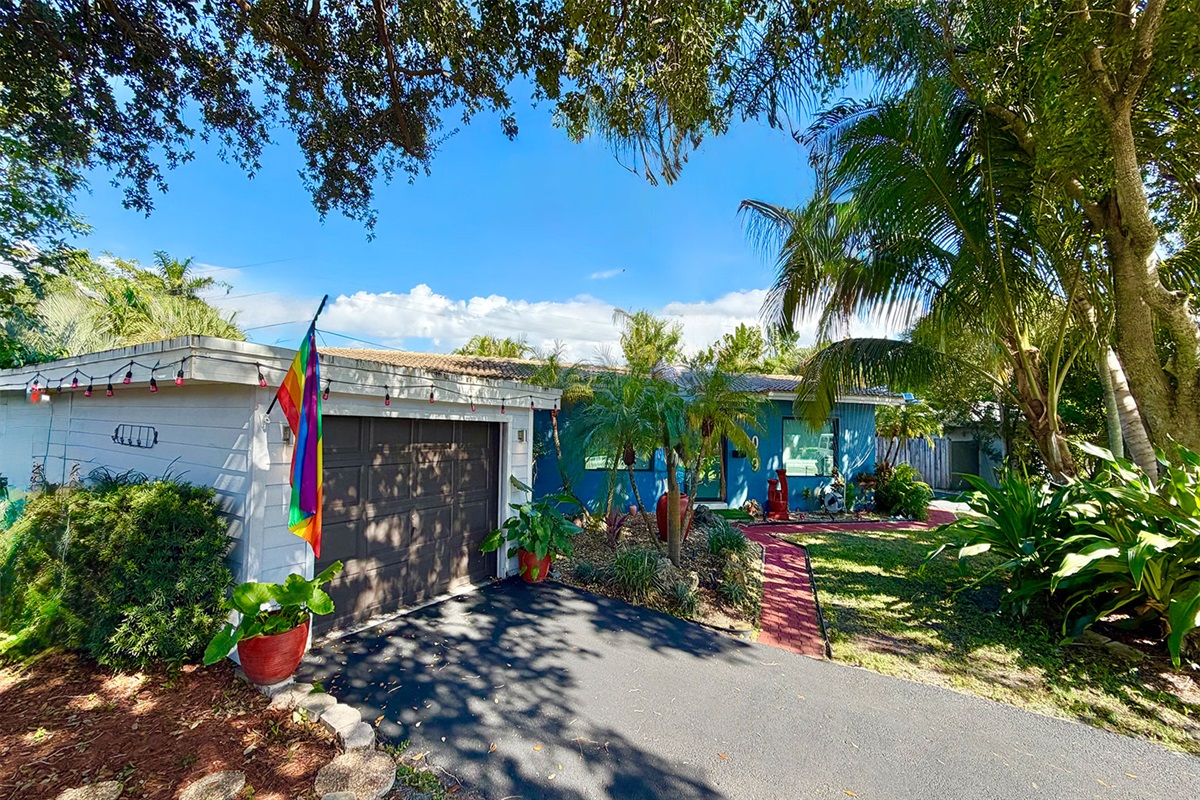 Garden of Manors exterior with tropical greenery, private driveway access, and a relaxed South Florida atmosphere.