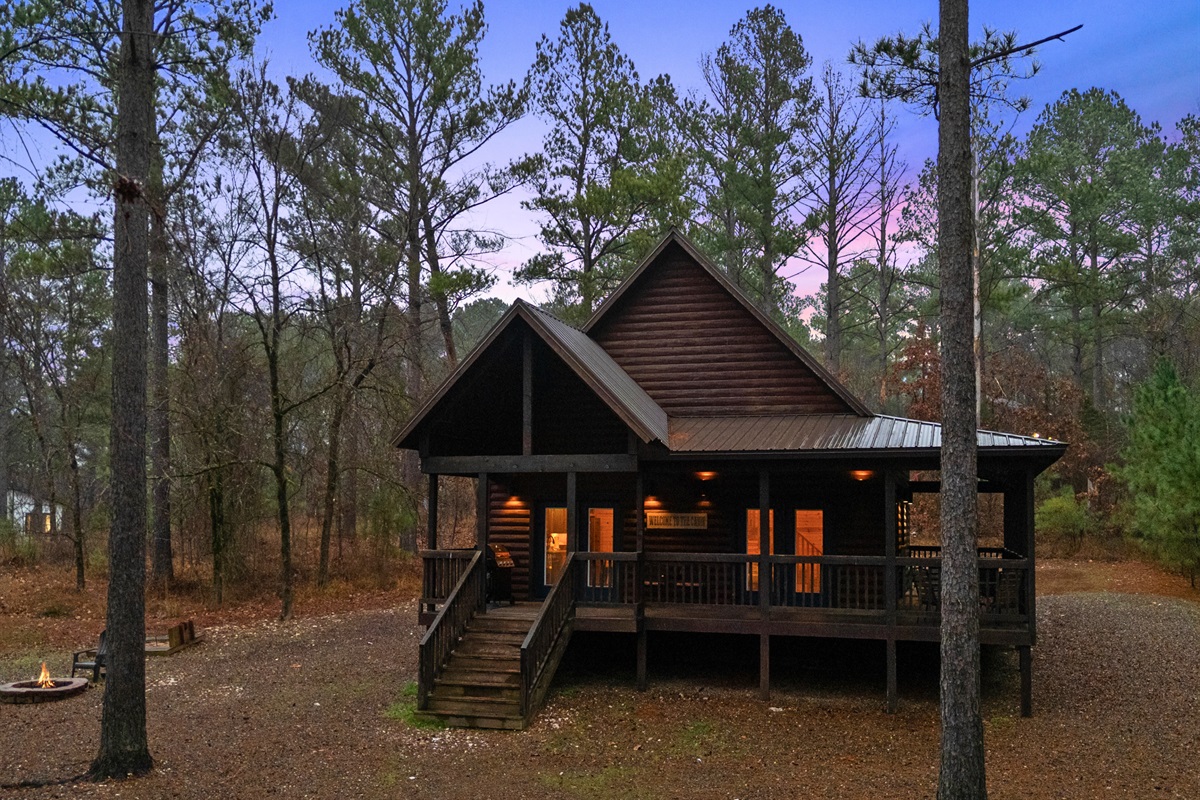 A front view of the cabin shows the welcoming covered porch and classic cabin design.