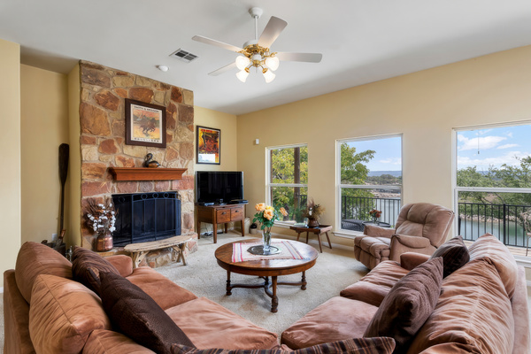 Living room with stone wood-burning fireplace and lake-view windows