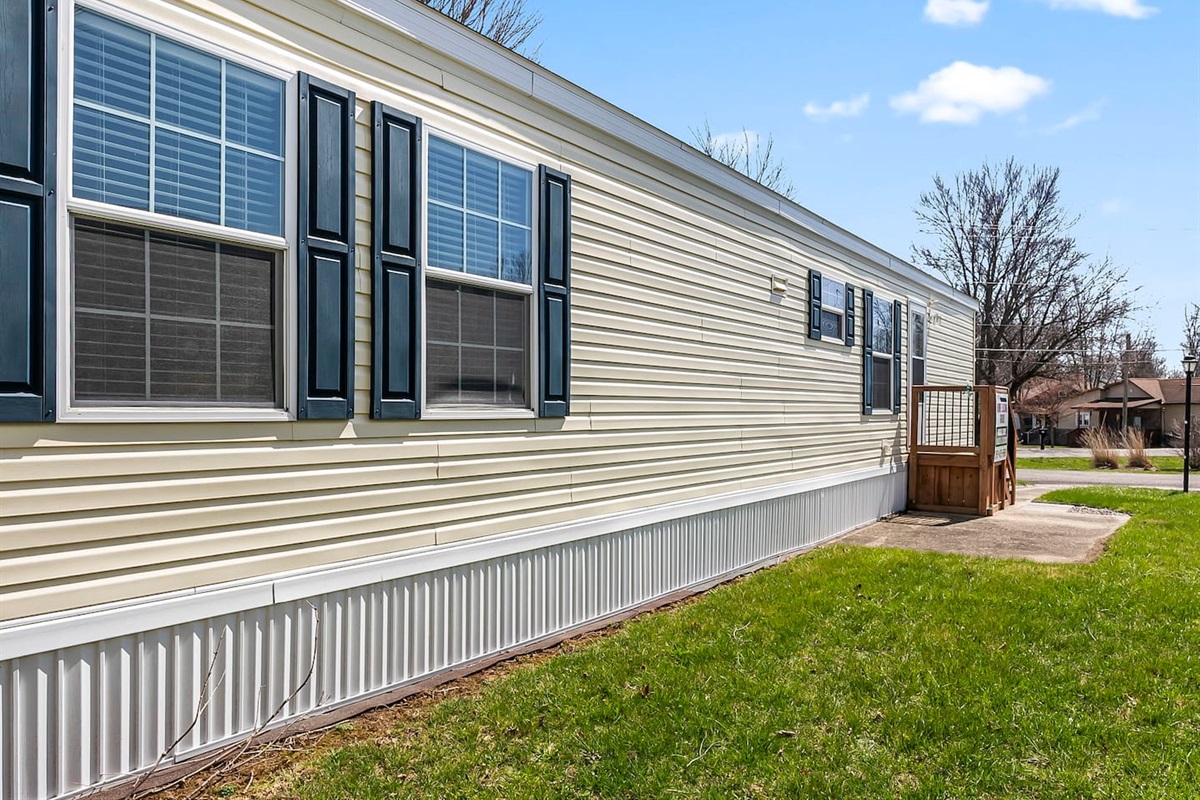 Side view highlighting the home’s length, multiple windows, and private entry steps.