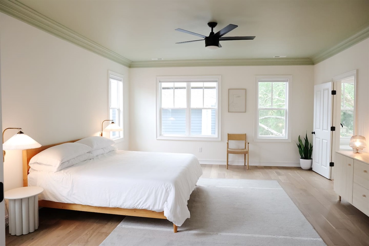 The spacious primary bedroom is a serene place to relax and recharge. The primary features a king sized bed, accents from CB2, walk-in closet, 50" Smart TV, and a full bath with a soaking tub and standup shower. 