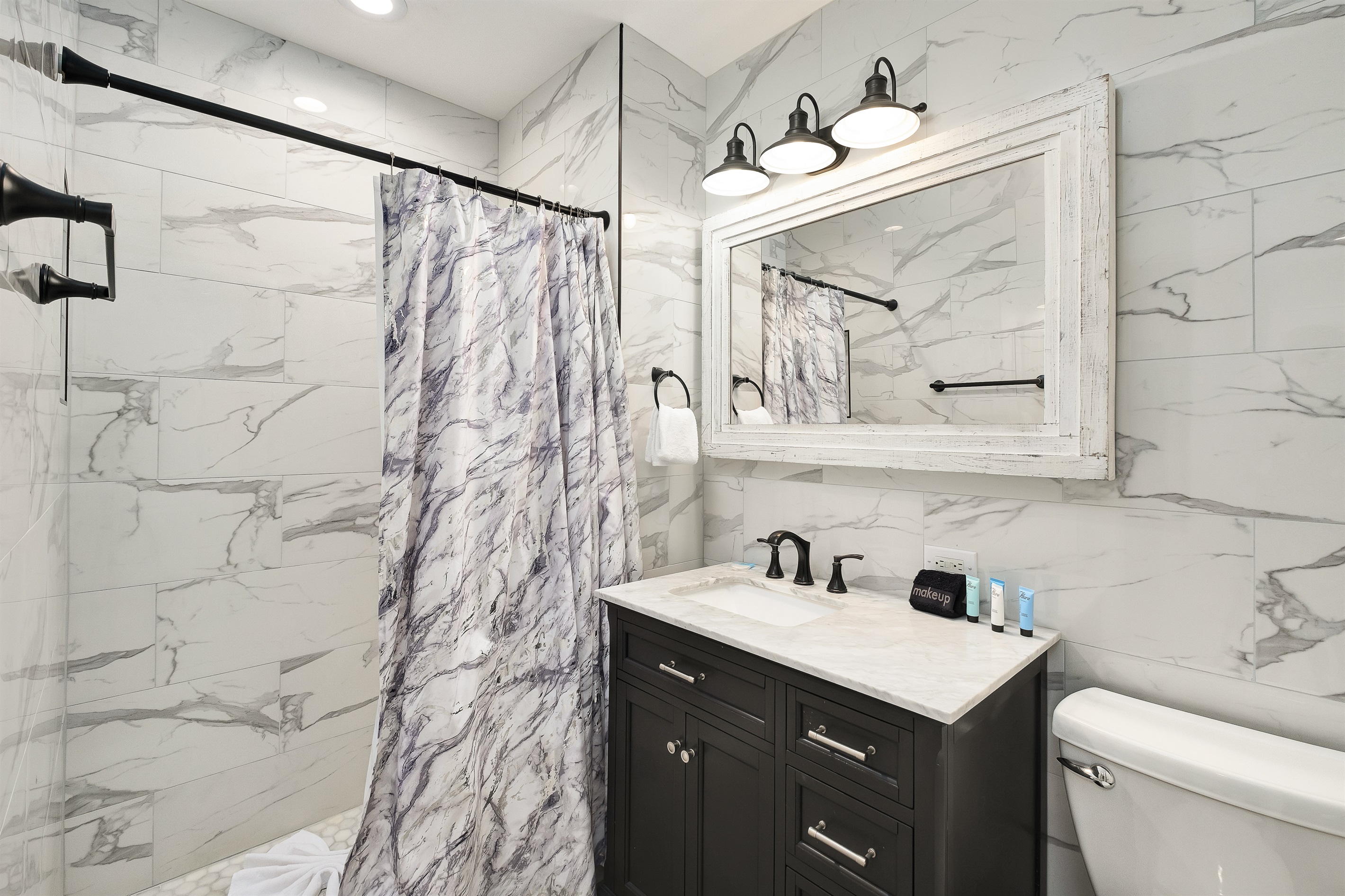 Step into luxury in this fully tiled bathroom featuring elegant marble finishes, modern lighting, and a chic vanity. Refresh yourself in this tranquil, spa-like space after a day of adventure.