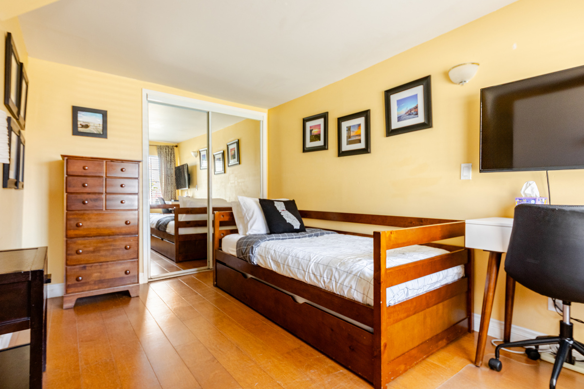 Bedroom #2 includes 2 single beds, a laptop workstation, tall dresser, full size closet and smart TV.
