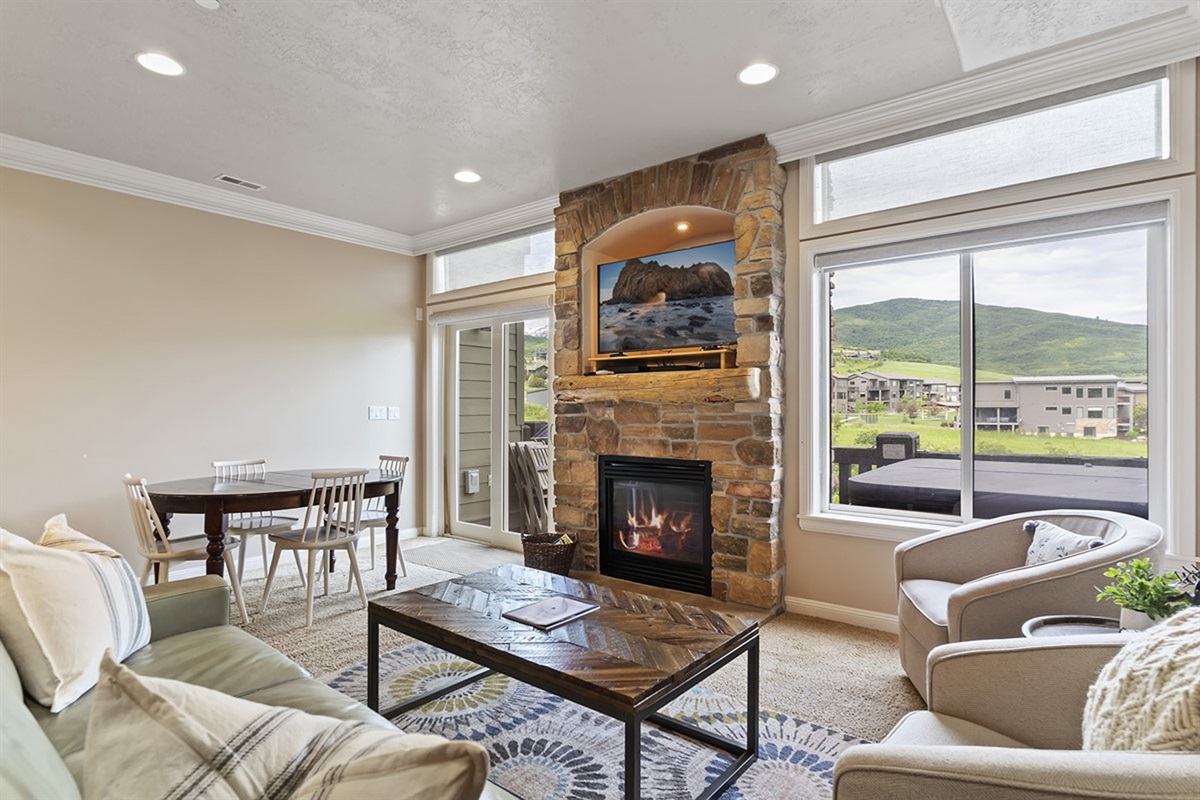 Living room with floor-to-ceiling gas stone fireplace, expansive windows, and breathtaking mountain views.