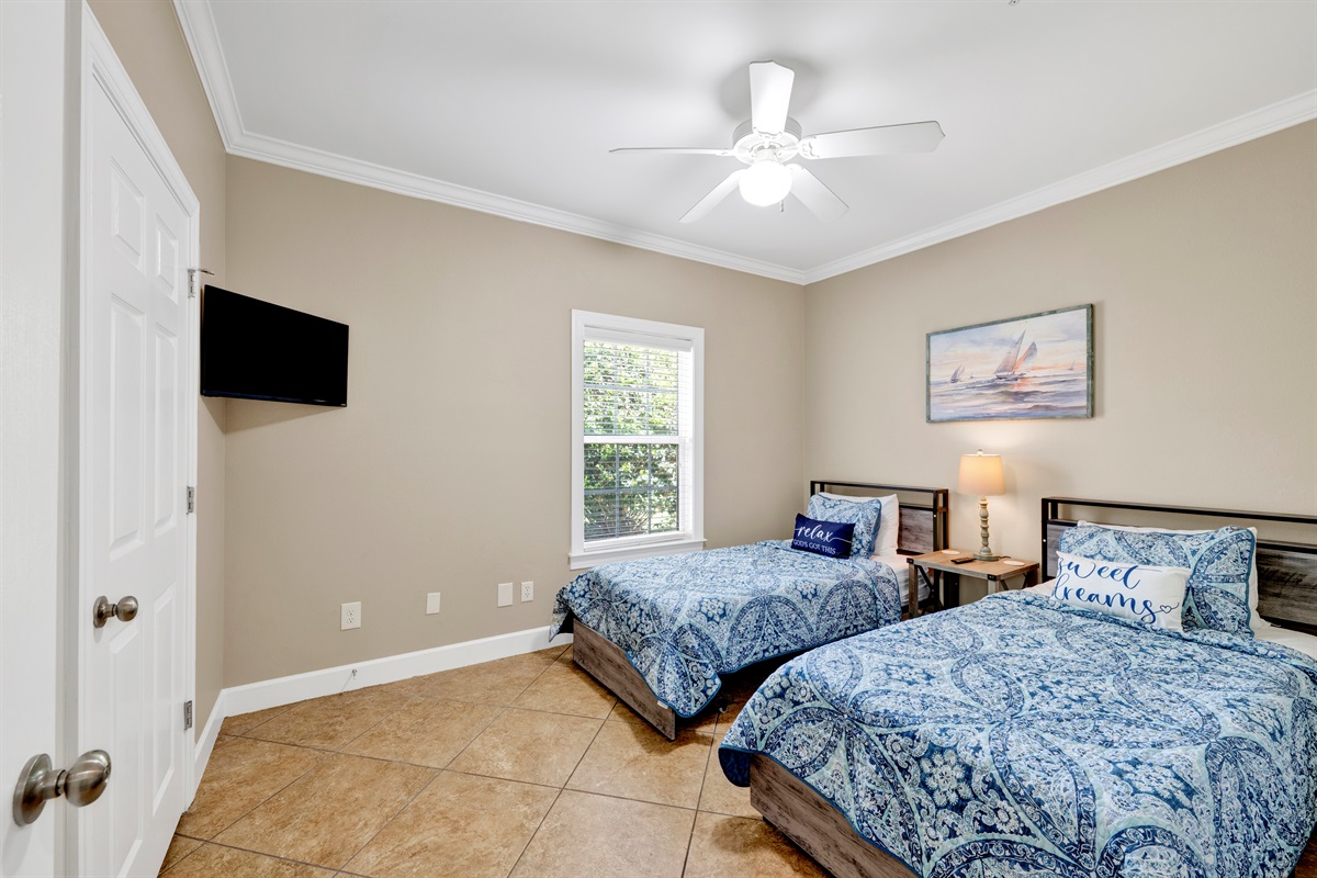 Bedroom 3 has 2 twin beds, ceiling fan and a wall mounted smart tv
