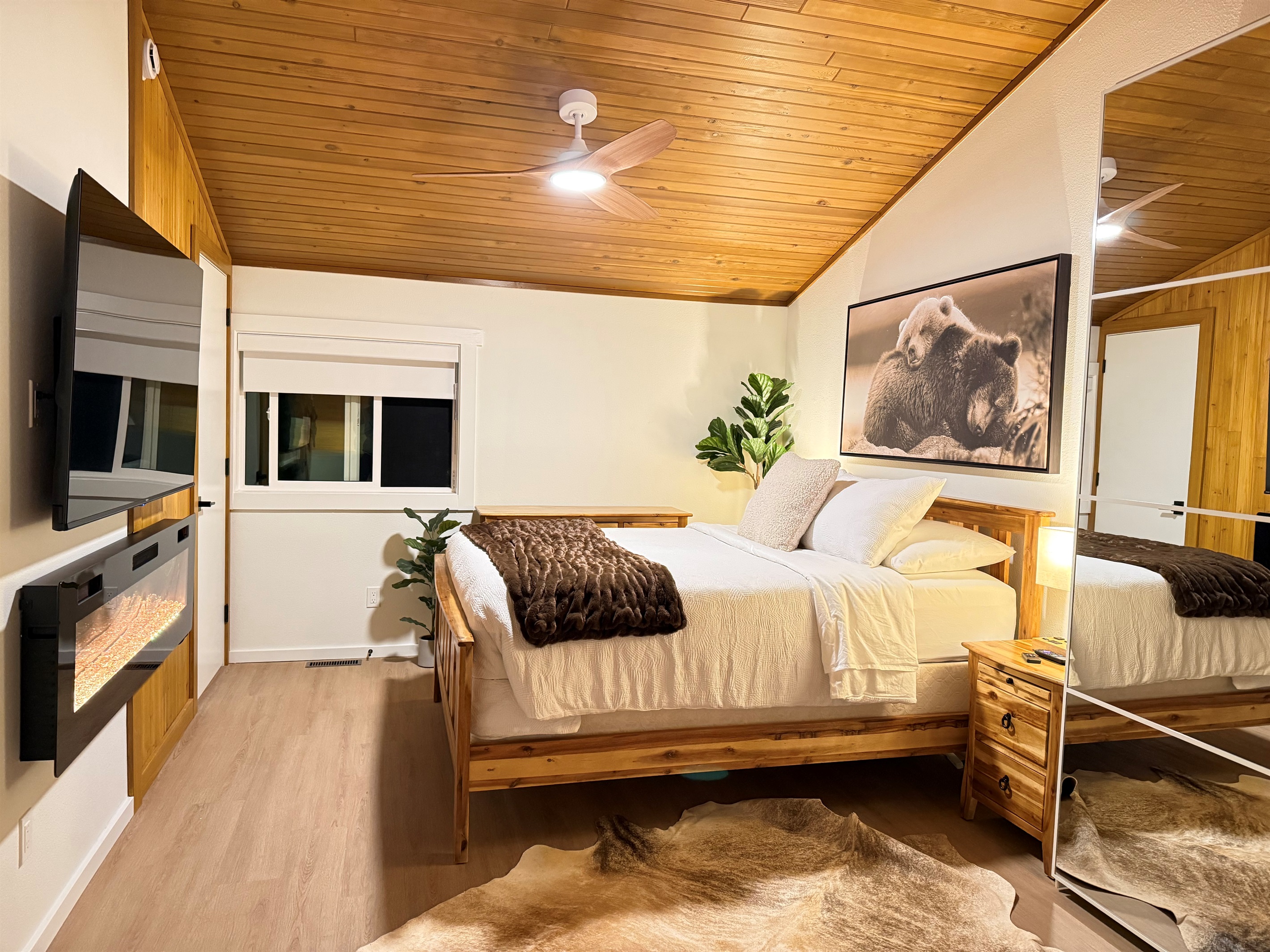 A romantic loft bedroom suite with alpine decor, a 65" TV, electric fireplace, closet and dresser storage. 