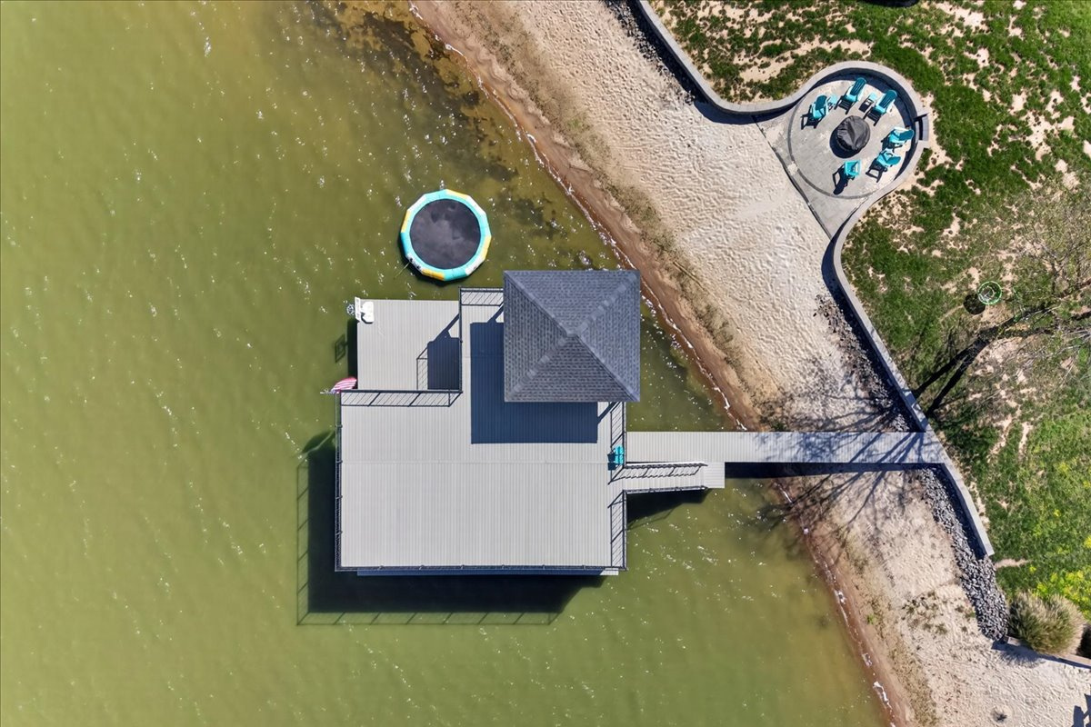 Bird’s-eye view of the boathouse, sandy beach, firepit area, and waterfront recreation space.