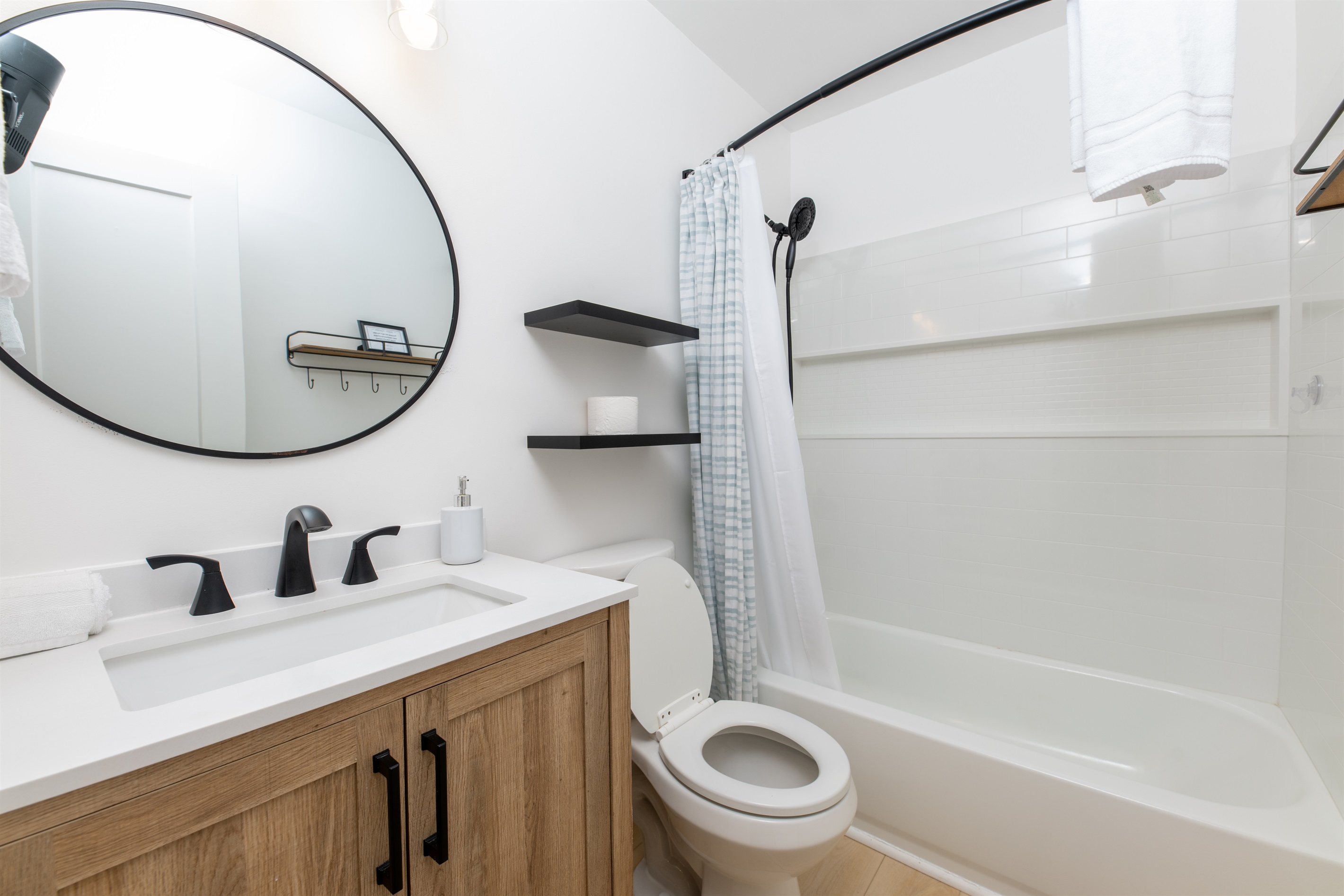 Updated bathroom with large tub/shower with a large shelf across the entire back