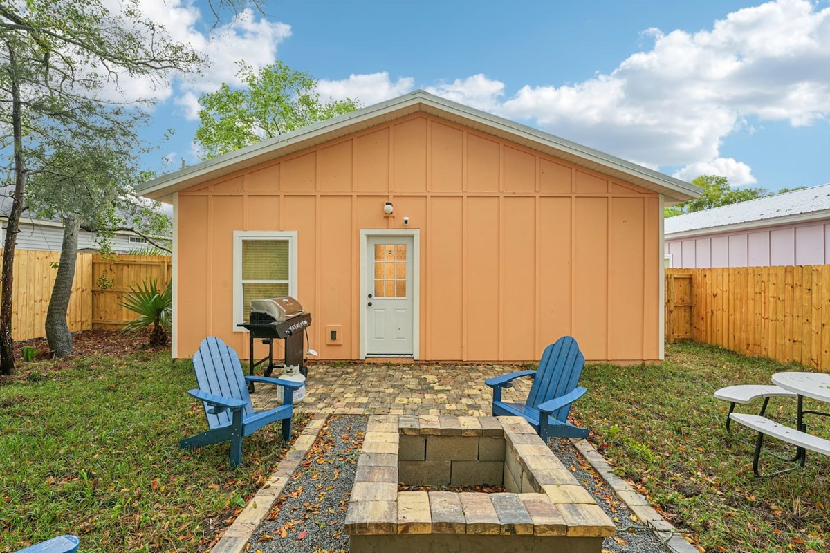Outdoor area has a stone patio, stone fire pit, 4 adirondak-style chairs, and an 8-seat picnic table, with a fully fenced, private backyard.