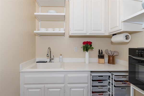 Kitchenette sink and prep area with cookware and utensils