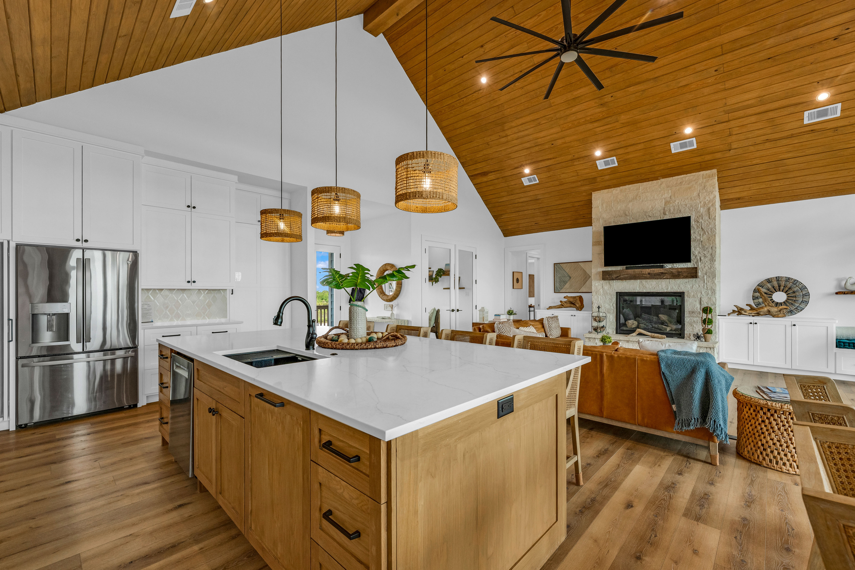 Cair Paravel: One sweeping look at the heart of the home: kitchen, dining, and living room united under vaulted wood ceilings, with the fireplace and Gulf views tying it all together.