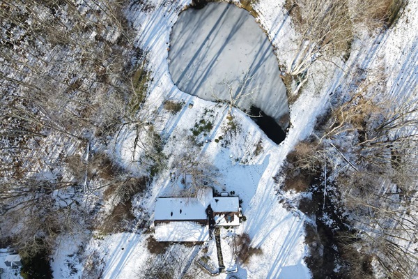 Higher altitude drone shot of pond, house and driveway.