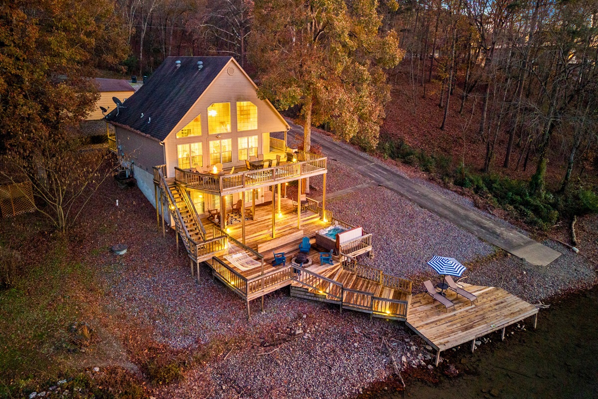 As evening settles in, the home lights up with a soft glow that enhances the peaceful lakeside setting and invites you to unwind outdoors.