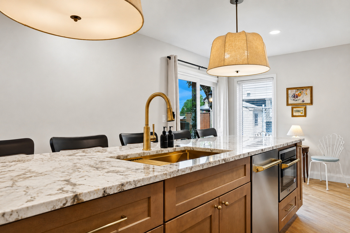 Bright, modern kitchen with quartz countertops, warm wood cabinetry, and a large island with seating. Open, stylish layout perfect for cooking, dining, and entertaining.
