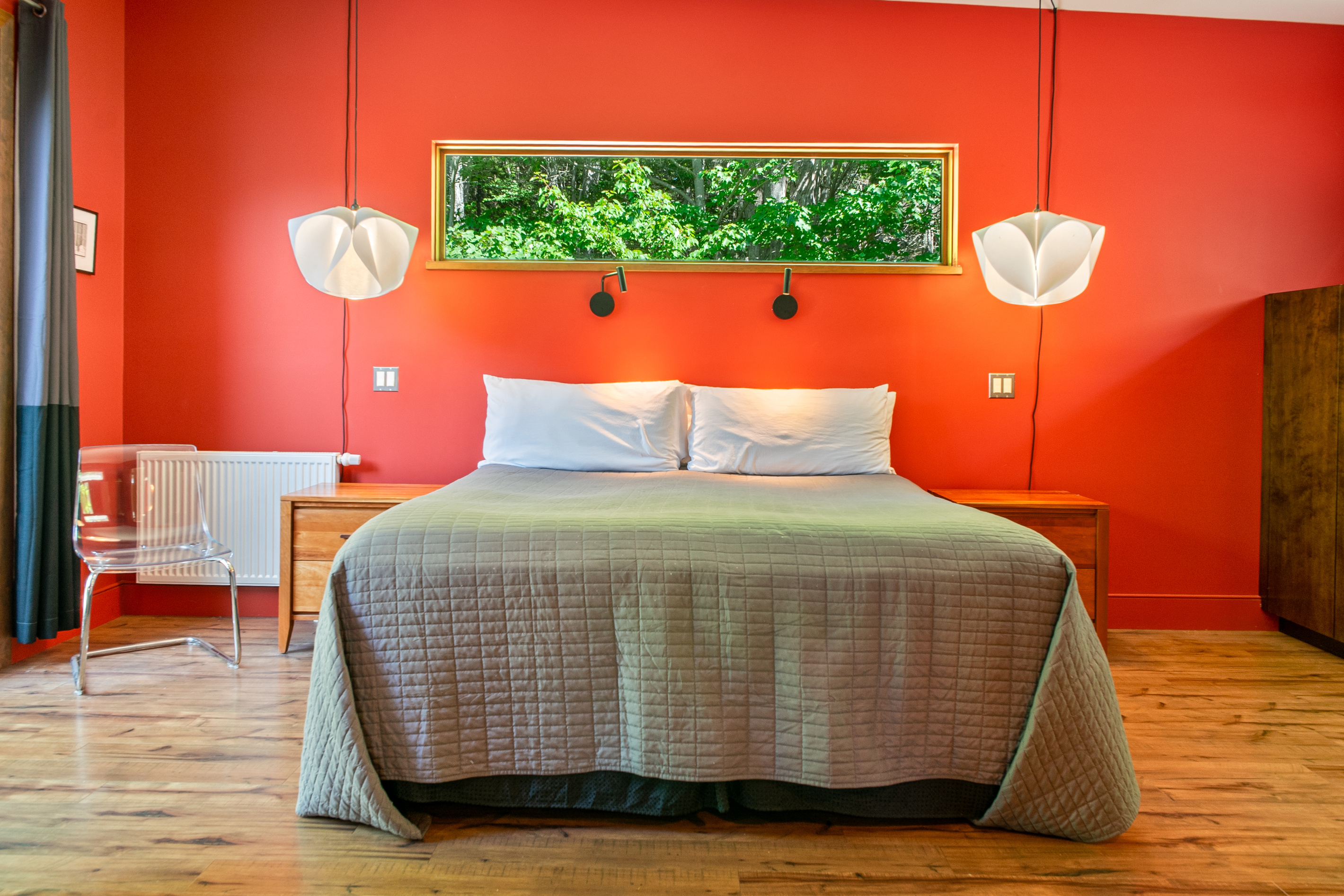 The sophisticated primary suite features a King bed and statement designer lighting. Enjoy direct, private access to the expansive deck through oversized glass doors, perfectly positioned to blend modern comfort with the natural beauty of the Acadia border