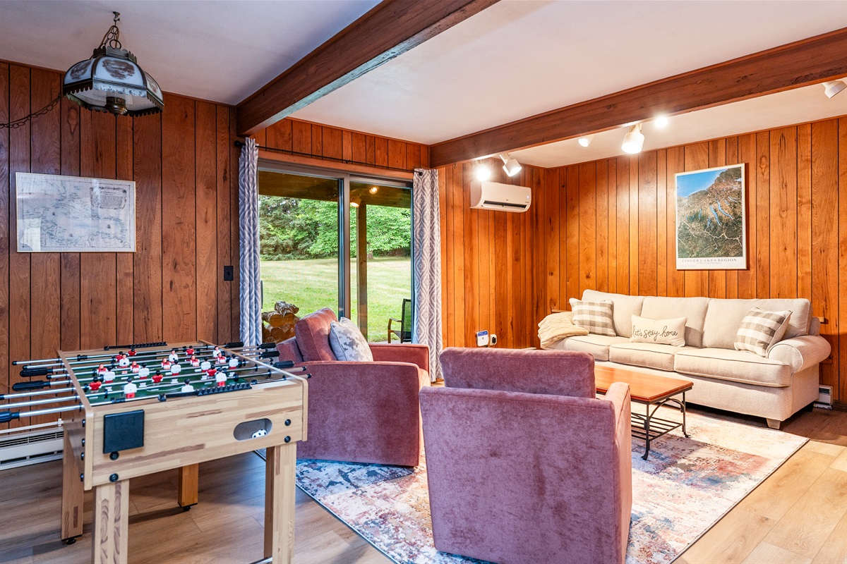 Fun-filled family room featuring foosball, plush seating, and sliding doors that open to the outdoors—ideal for game nights and relaxation.