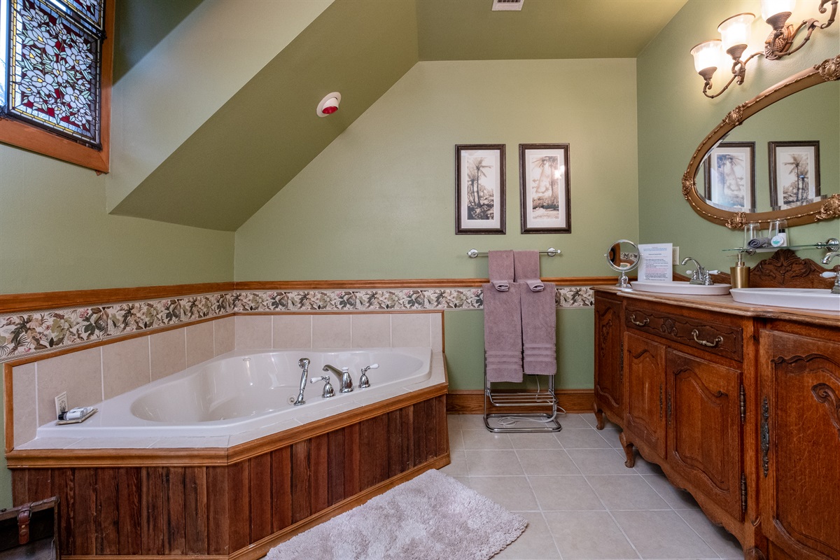 Spa-style bathroom featuring a jetted soaking tub, custom wood vanity, and soft, ambient lighting.