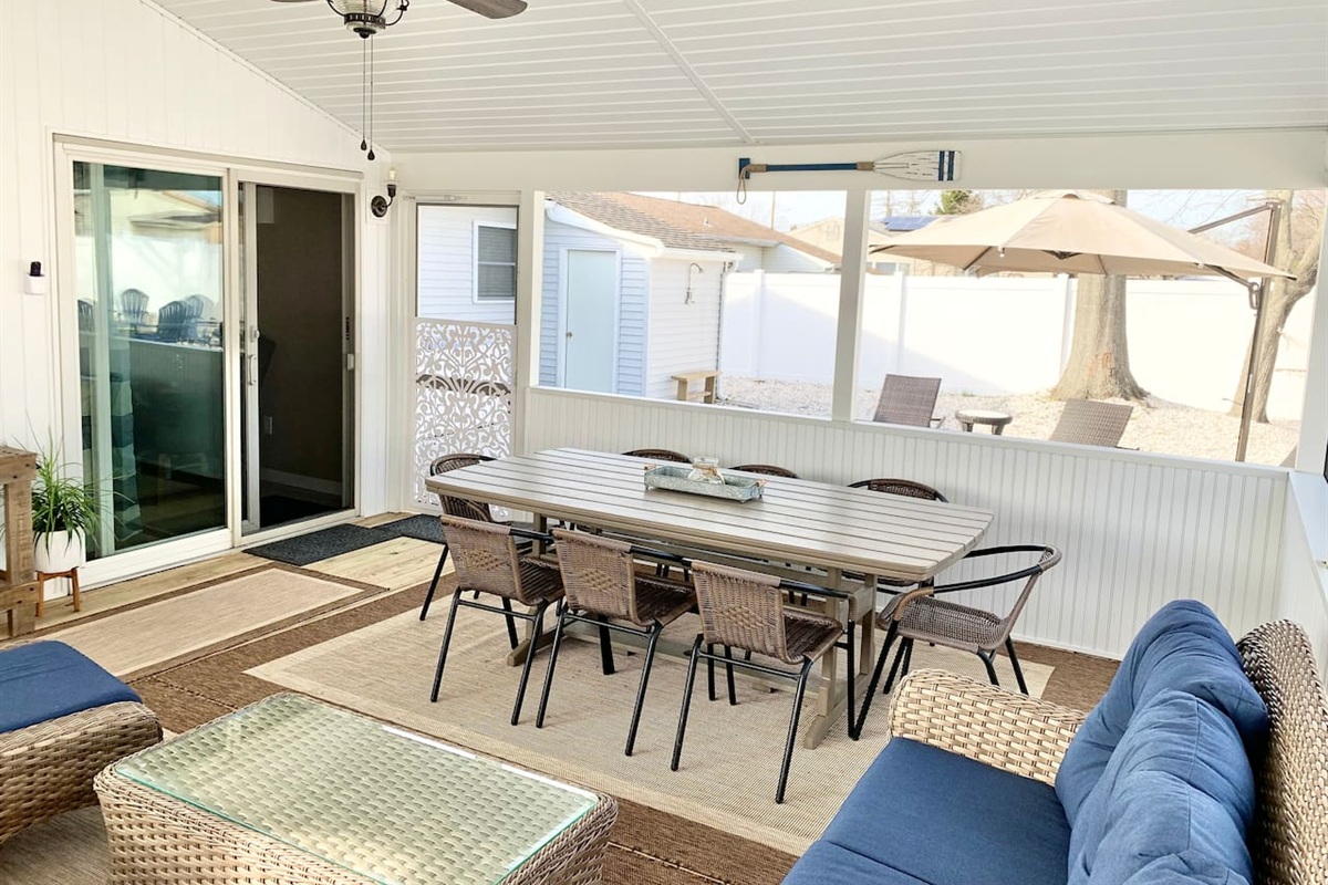 Experience the best of indoor-outdoor living in our screened-in sunroom. Kick back on navy wicker seating to watch the game or enjoy a meal at the large dining table—all while staying protected from the elements in a bright, coastal setting.