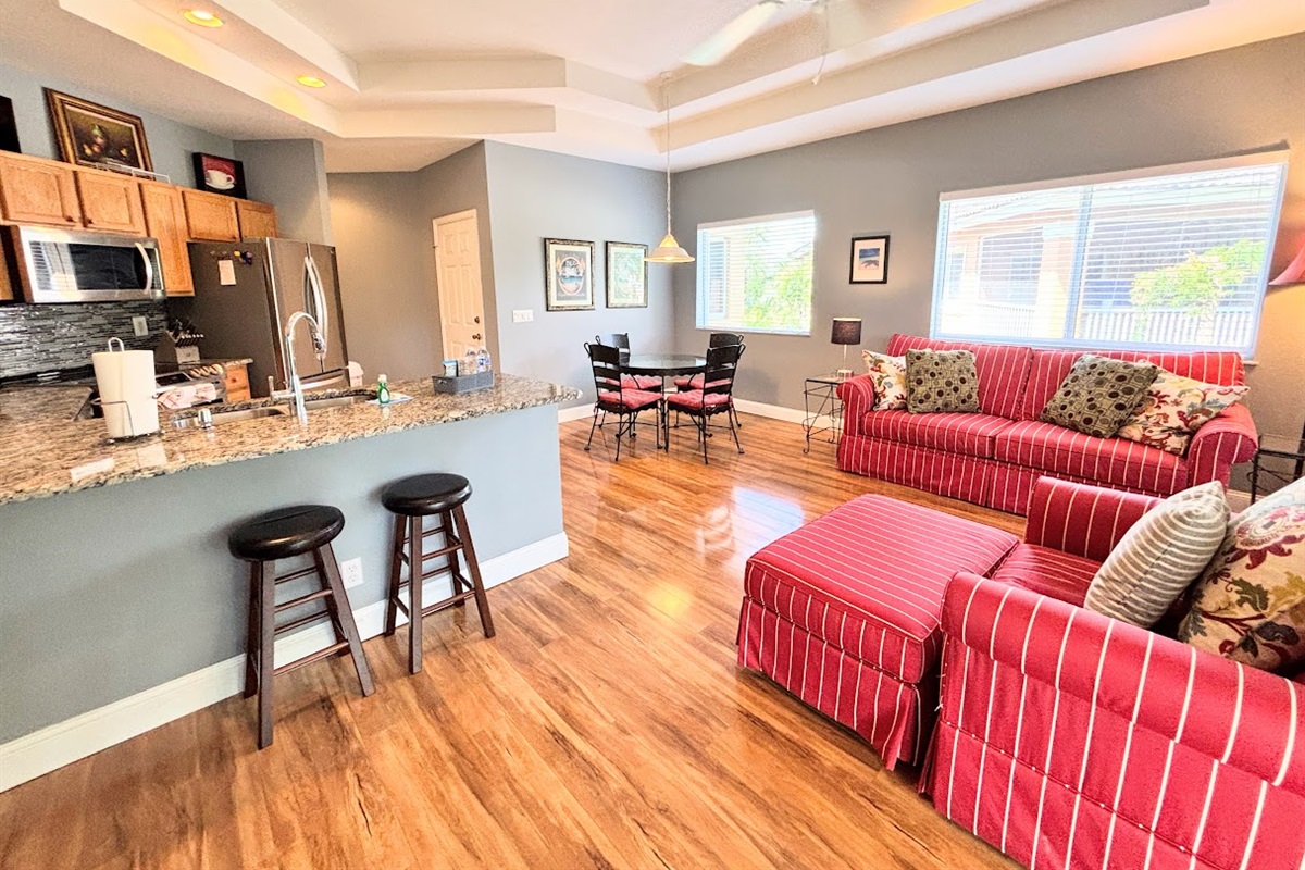 Open kitchen and living space with breakfast bar seating, updated flooring, and a bright, welcoming layout.