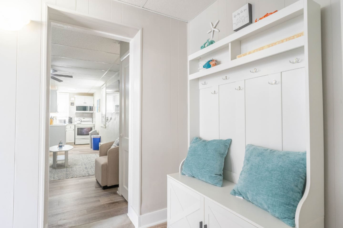 Entryway with built-in bench seating, coat hooks, and storage below. A clean, functional space for shoes and bags, offering a comfortable drop zone that keeps the main living areas organized and uncluttered.