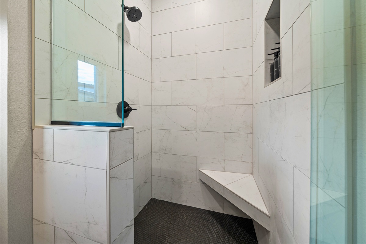 This large walk-in shower includes convenient bench seating and is beautifully tiled for a luxurious feel