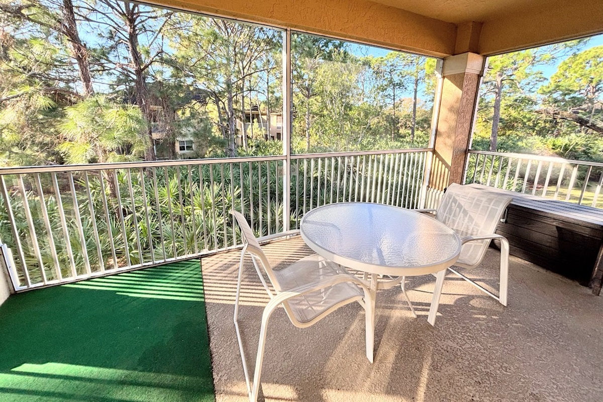 Private screened balcony with outdoor seating and peaceful views of the surrounding trees — a perfect spot for morning coffee or evening relaxation.