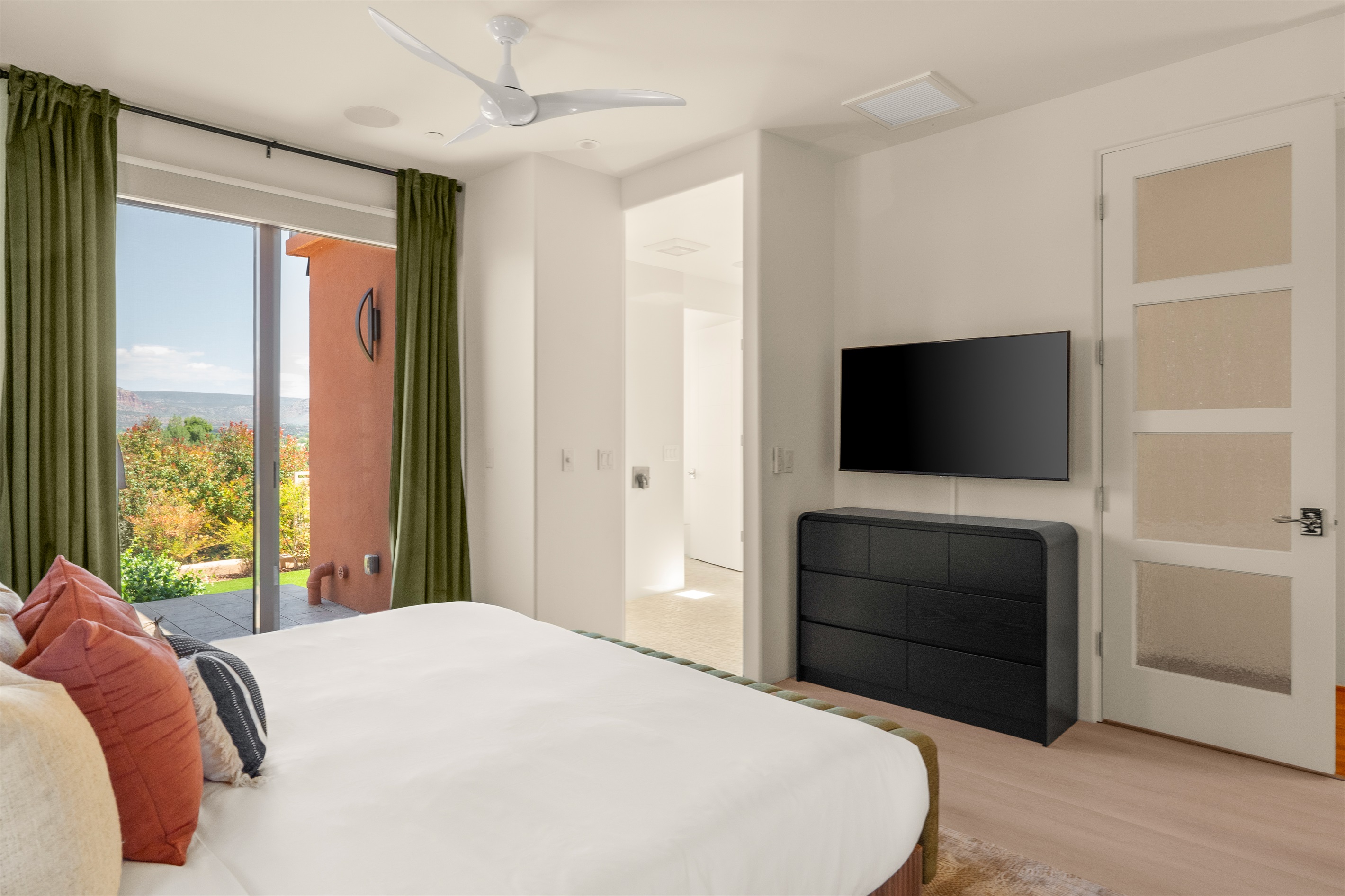 A bright, modern bedroom featuring a large Smart TV, premium linens, and private sliding glass doors that open directly to the outdoor patio.