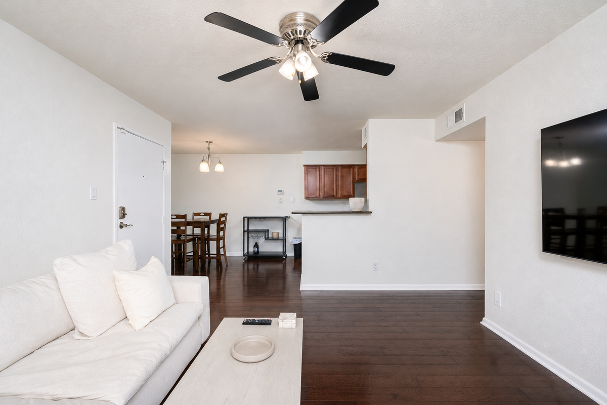 Open in-unit living area with sofa seating, Smart TV, ceiling fan, and easy flow to the dining space and kitchen.